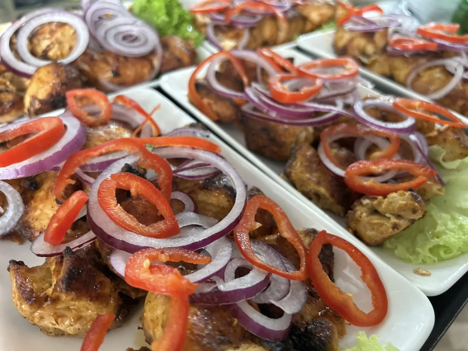 Plated mtsvadi (Georgian skewers) topped with red onions and chilies